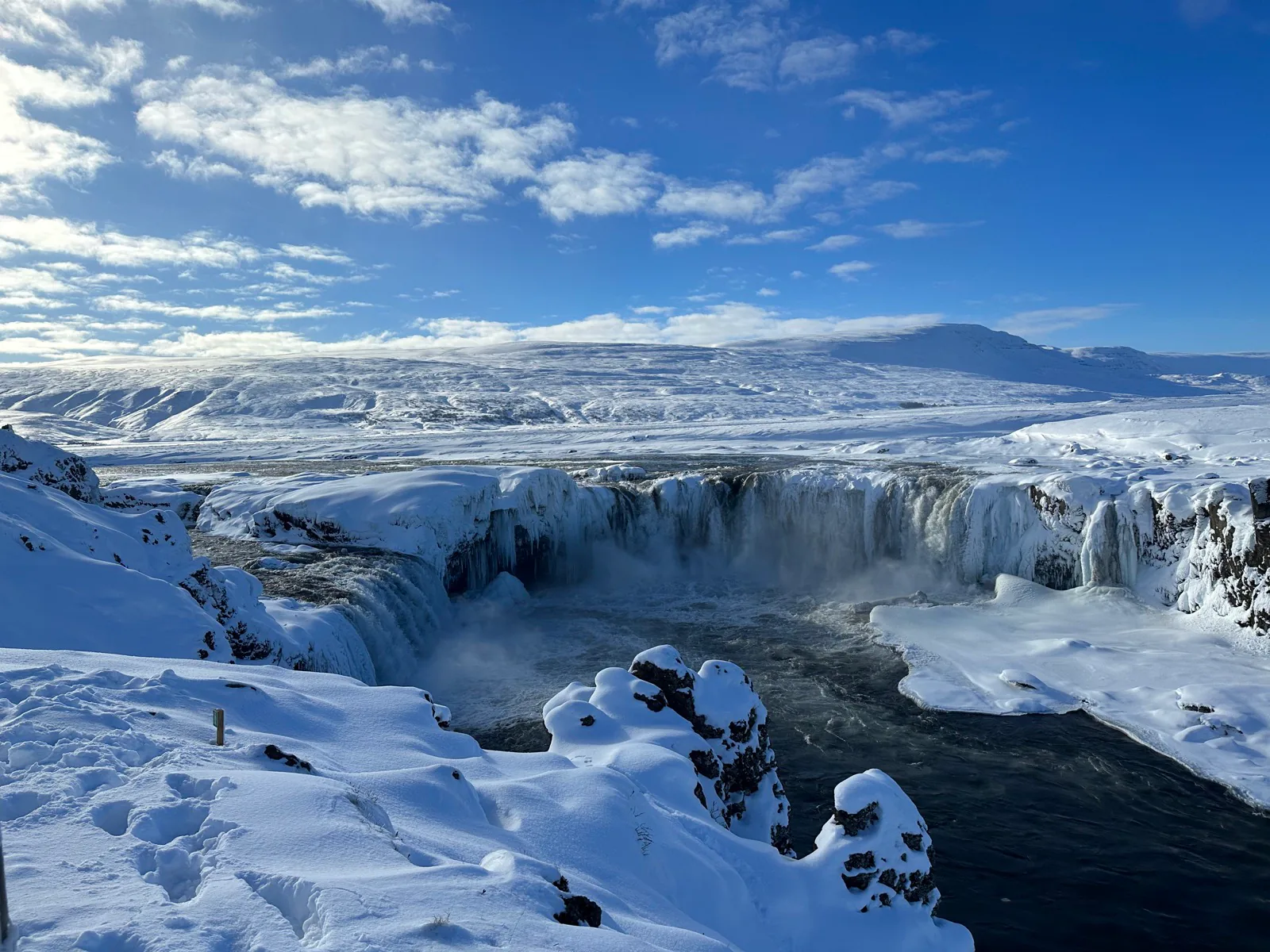 A snow-covered waterfall beneath a bright blue sky