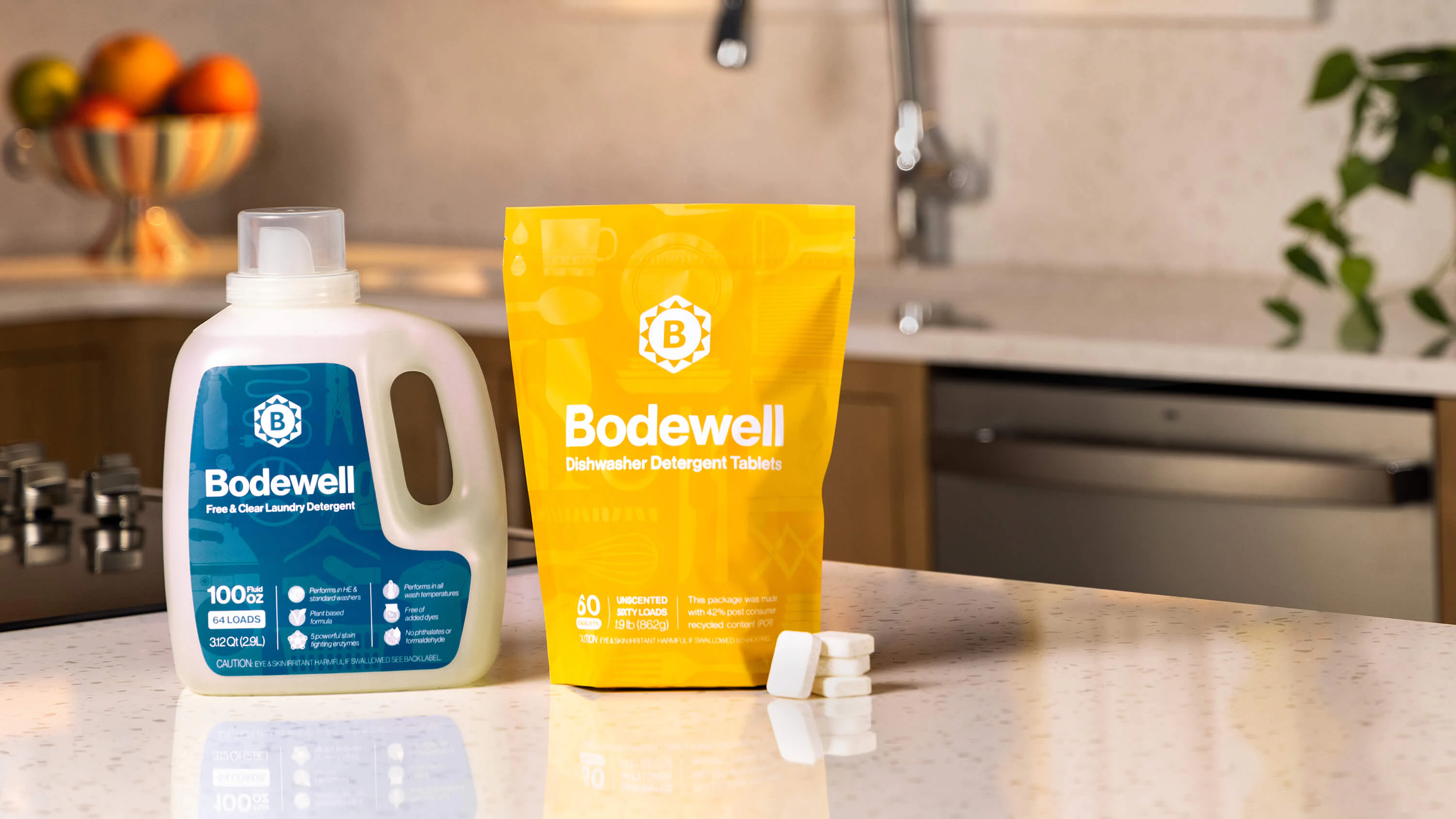 A full bottle of Bodewell laundry detergent and a full package of dishwasher tablets shown together in a kitchen